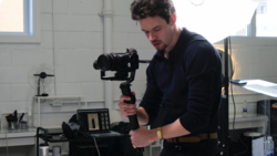 Videographer operating a motorized gimbal stabilizer in a bright studio space