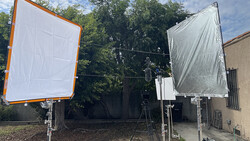 Two large fabric reflectors with orange and silver frames mounted on stands in a residential outdoor space