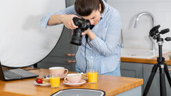 Photographer shooting a styled food setup with a mirrorless camera on a tripod in a bright kitchen.