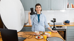 Content creator in a kitchen studio with professional lighting setup and camera equipment.