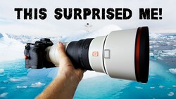 Photographer holding a white telephoto lens with red accents against an aerial landscape of blue water and snowy terrain.