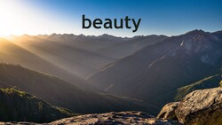 Mountain valley at sunrise with layered peaks, forested slopes, and golden sunlight filtering through atmospheric haze.