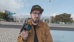 Photographer holding a thermal imaging camera while posing outdoors in urban setting.