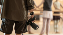 Photographer holding a DSLR camera with telephoto lens at a professional event