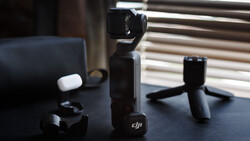 DJI Osmo Pocket gimbal camera with accessories displayed on a dark table.
