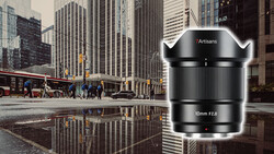 Artisans 10mm f2.8 ultra-wide lens product shot displayed over urban street reflection