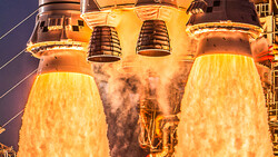 Space shuttle main engines igniting at night, producing bright yellow exhaust plumes against dark sky.