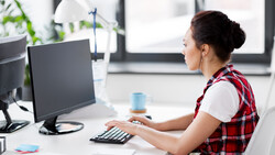 Woman at desk working on desktop computer in bright office environment