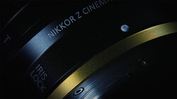 Close-up of a Nikkor Z Cinema lens with focus ring and depth of field markings visible against dark background.