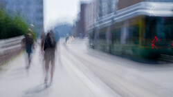 Blurred urban street scene with pedestrians and passing transit bus