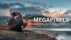 Shipwreck beached on rocky shore with mountains in background and text overlay about megapixels.