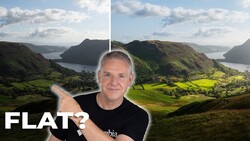 Man in black shirt pointing at mountainous valley landscape with bay and green fields.