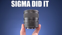 Sigma 16mm f/1.4 DC HSM lens held in hands against blue background.