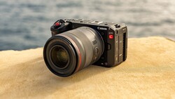 Canon EOS R5C mirrorless camera with RF lens on sandy beach with ocean in background.