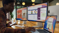 Creative professional working at wooden desk with laptop and dual monitors displaying data visualizations