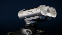Vintage camera flash mounted on Canon DSLR against dark blue background