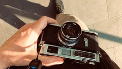 Photographer's hands holding a vintage rangefinder camera in bright sunlight