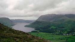 Mountain lake valley landscape with layered peaks under dramatic overcast sky