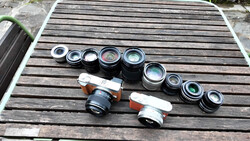 Collection of vintage rangefinder camera lenses and two film camera bodies arranged on wooden surface