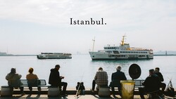 People sitting on a waterfront bench overlooking ferries on the Golden Horn in Istanbul
