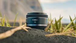 Canon RF 50mm lens positioned on textured ground with shallow depth of field