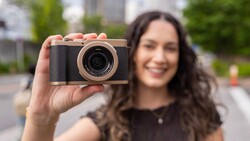 Woman holding a compact digital camera with black body and rose gold accents