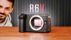 Canon R6V mirrorless camera displayed on wooden surface with portrait in background