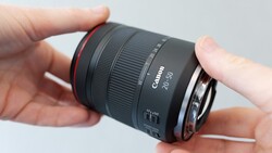 Canon RF 24-50mm lens held in hands against neutral background