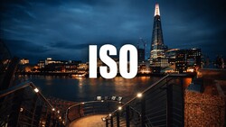 Large white "ISO" text overlaid on twilight cityscape with illuminated riverside buildings and tower