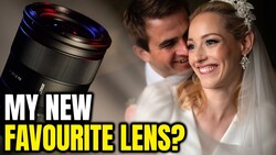 Prime lens with blue-tinted focus ring next to couple in wedding attire