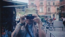 Photographer holding vintage film camera up to face in urban plaza