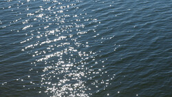 Sunlight glinting off calm ocean water creating sparkling reflections across the surface