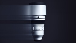 Silver telephoto lens with focus ring and distance scale against dark background