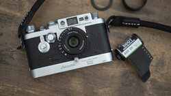 Voigtländer rangefinder camera with film canister and accessories on textured surface