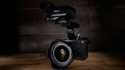 Sony mirrorless camera with telephoto lens and external microphone mounted on wooden surface
