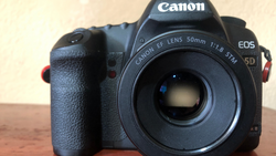 Canon EOS 5D DSLR with Canon EF 50mm f/1.8 STM lens mounted, displayed on wooden surface