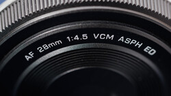 Close-up of AF 28mm 1:4.5 VCM ASPH ED camera lens barrel against blue sky
