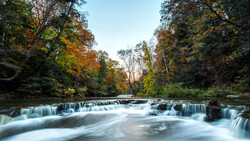 Cascading waterfall flowing through autumn woodland with smooth long-exposure water effect