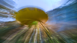 Radial zoom blur of yellow disc above rural landscape with trees and sky