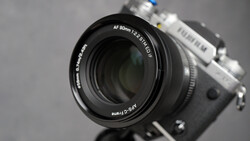 Fujifilm camera with AF 90mm f/2.4 R LM OIS lens mounted, shot against neutral gray background