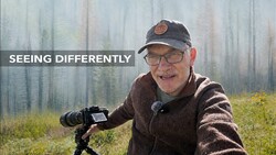 Photographer with thermal imaging camera on tripod in misty forest landscape