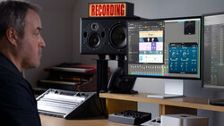 Audio engineer at professional recording studio workstation with dual monitors and studio speakers