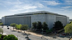 Modern concrete performing arts building with vertical ribbed facade and plaza seating