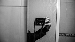 Photographer's hand holding vintage rangefinder camera in bathroom mirror selfie