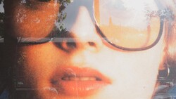 Double-exposure portrait of a person wearing oversized glasses with warm, golden-hour lighting overlaid with architectural elements