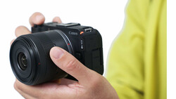 Hand holding a compact mirrorless camera with black body and lens
