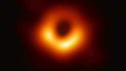 First photograph of a black hole showing bright orange and yellow accretion disk with dark central shadow