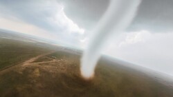 Tornado funnel cloud touching ground in rural landscape viewed from aircraft