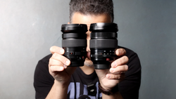 Photographer holding two vintage camera lenses up to face
