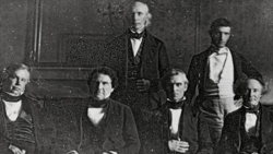 Five men in formal 19th-century attire arranged in a studio portrait